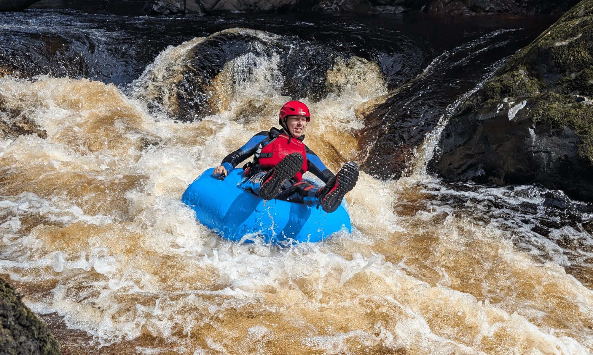 river tubing through white water rapids with waterfalls and rapids behind them.